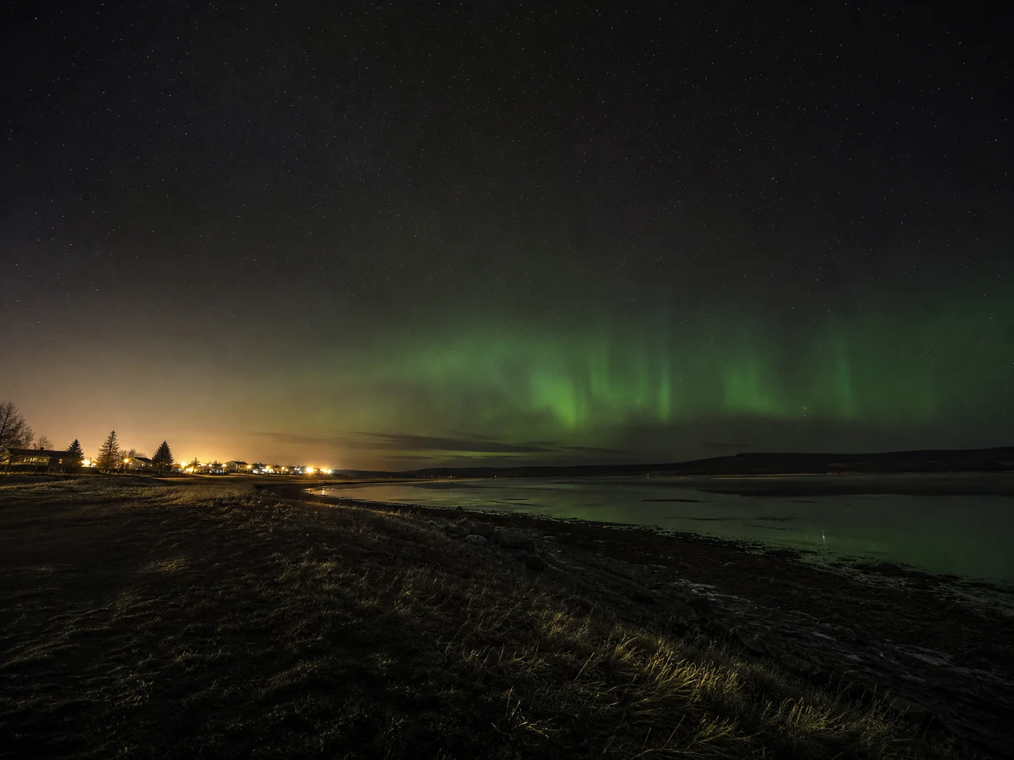 An AI-created northern town edge with aurora beyond the street lights