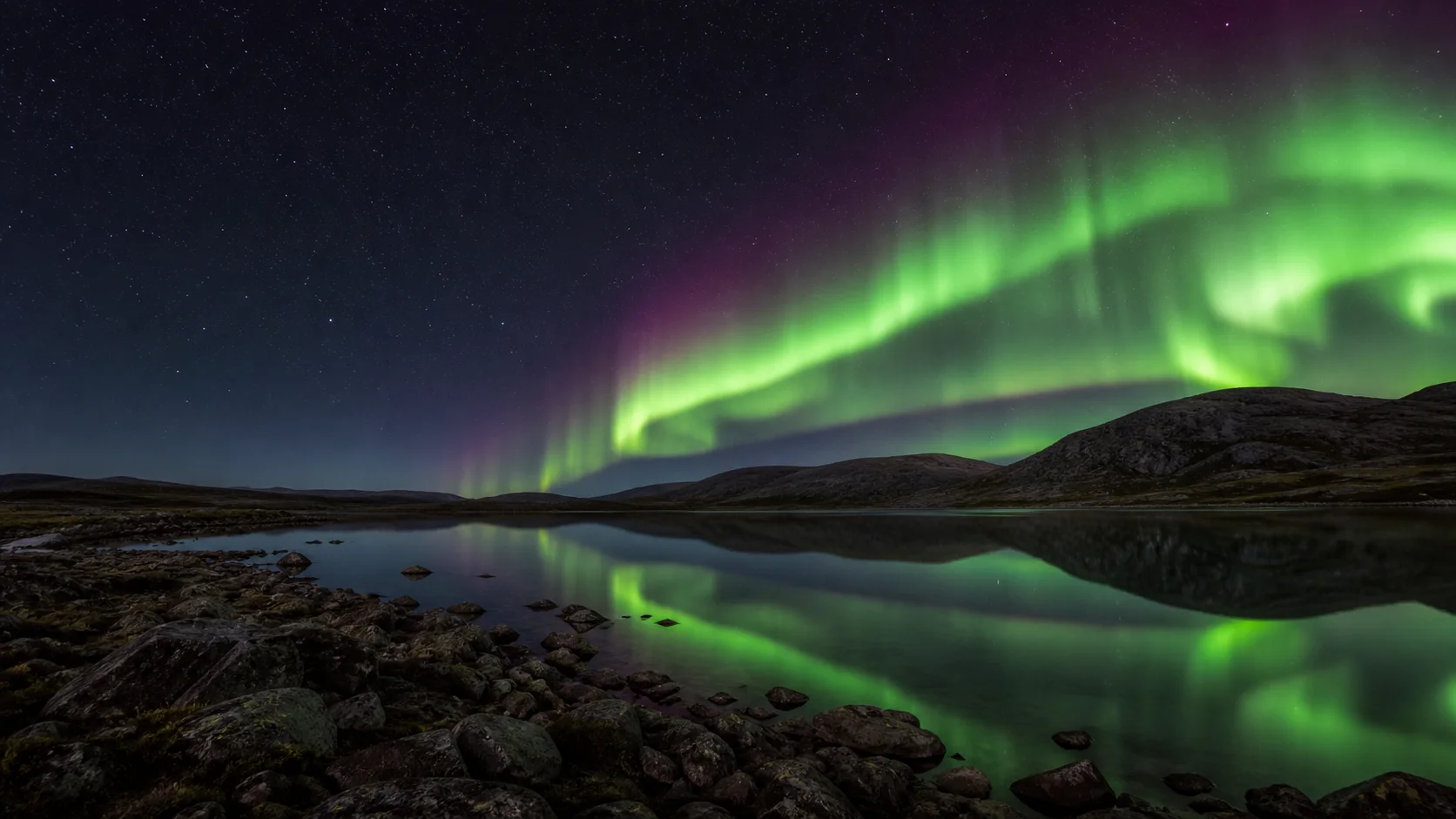 An AI-created aurora sweeping over a still mountain lake at night